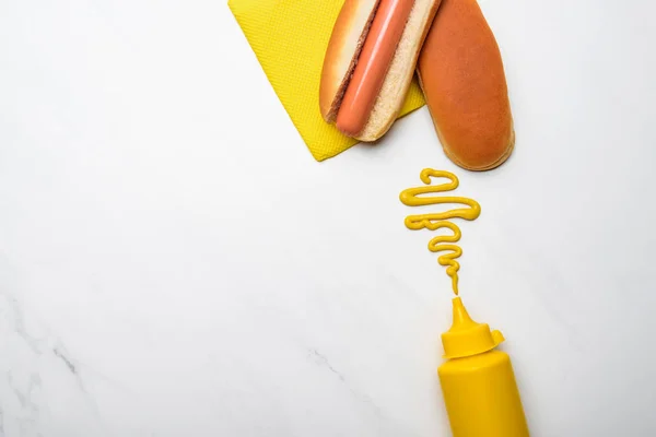 Vista superior de cachorro-quente saboroso com mostarda na superfície de mármore branco — Fotografia de Stock