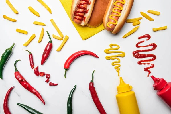 Top view of delicious hot dogs and peppers with mustard and ketchup on white marble surface — Stock Photo