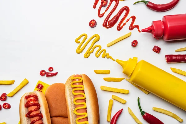 Vista superior de saborosos cachorros-quentes e batatas fritas com mostarda e ketchup na superfície branca — Fotografia de Stock