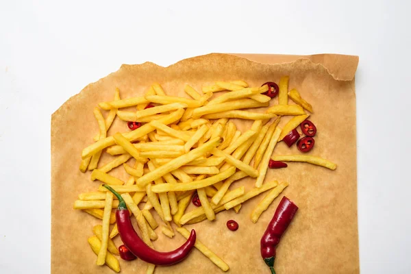 Vista dall'alto di patatine fritte con peperoni piccanti su carta pergamena isolata su bianco — Foto stock