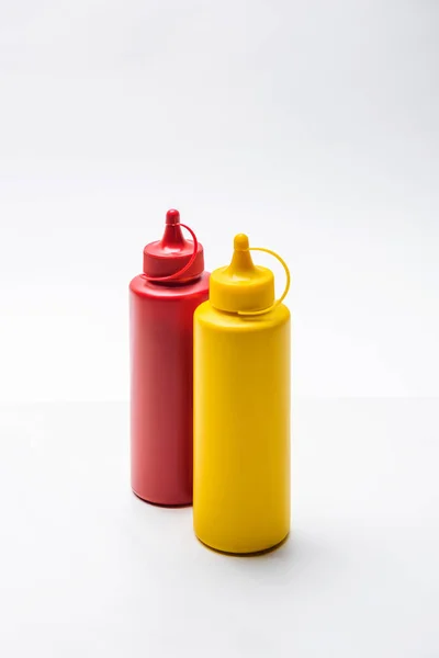 Close-up shot of bottles of ketchup and mustard on white tabletop — Stock Photo