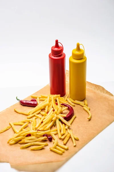 Primer plano de papas fritas con pimienta, ketchup y mostaza sobre blanco - foto de stock