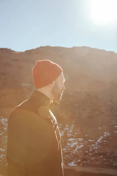 Handsome young man in red hat looking away in front of mountain on sunny day, Carpathians, Ukraine — Stock Photo