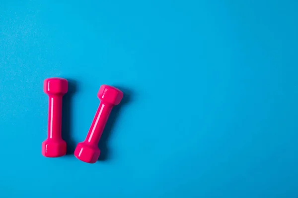 Flat lay with pink dumbbells isolated on blue, minimalistic concept — Stock Photo