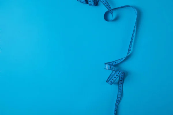 Top view of measuring tape isolated on blue, minimalistic concept — Stock Photo