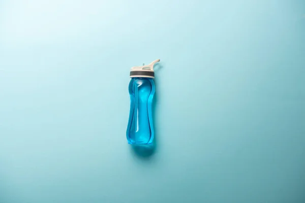 Erhöhte Ansicht der Sportflasche isoliert auf blauem, minimalistischem Konzept — Stockfoto