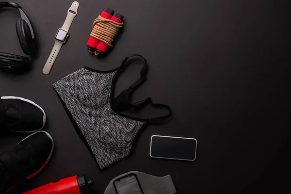 Flat lay com conjunto arranjado de equipamento de ginásio isolado em preto — Fotografia de Stock