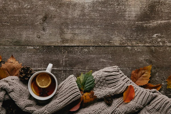 Flat lay with grey sweater, fallen leaves and cup of tea on wooden tabletop — Stock Photo