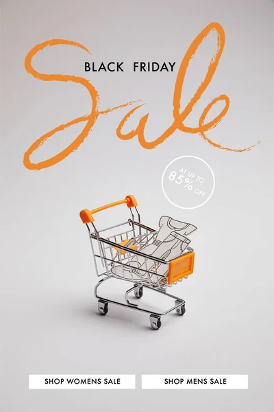 Close up view of shopping cart with little goods made of paper on grey background, black friday sale inscription — Stock Photo