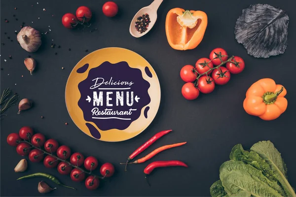 Top view of bell peppers and cherry tomatoes with yellow plate with menu lettering on gray table — Stock Photo