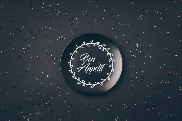 Top view of black plate with bon appetit lettering on gray table — Stock Photo