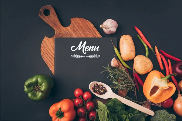 Vista superior de pizarra negra con letras de menú en mesa de madera con verduras en mesa gris - foto de stock