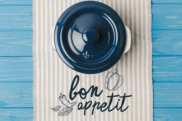 Top view of pan on napkin on blue wooden table, bon appetit lettering — Stock Photo