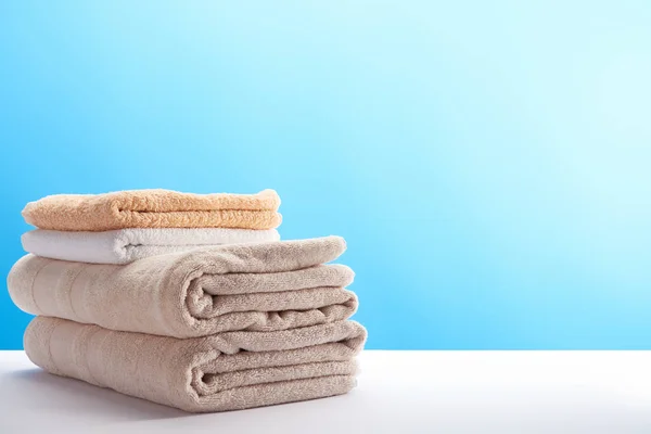 Pila de toallas suaves frescas limpias sobre fondo azul - foto de stock