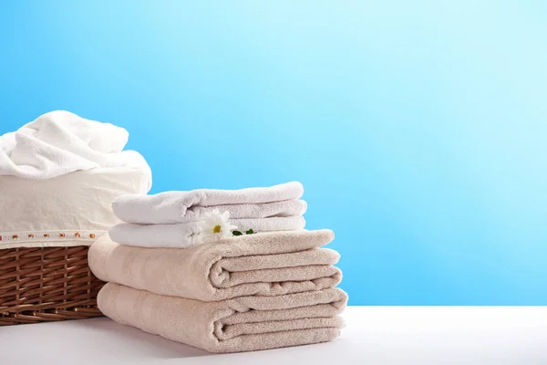 Cesta de roupa, toalhas e camomila flor em azul — Fotografia de Stock
