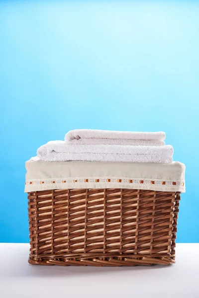 Vue rapprochée du panier à linge avec serviettes propres et douces sur bleu — Photo de stock