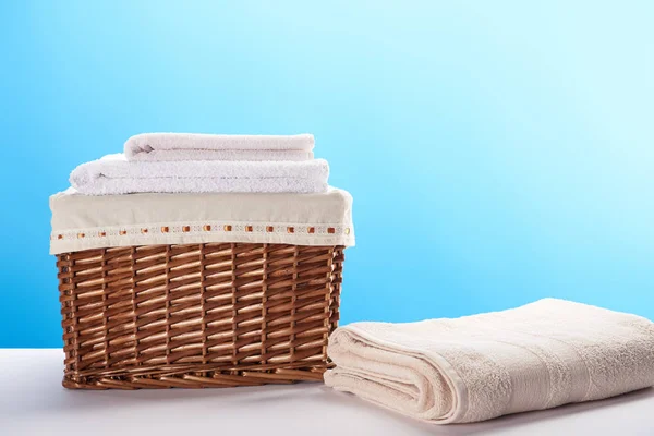 Laundry basket and clean soft towels on blue — Stock Photo