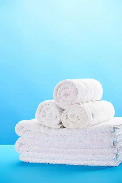 Close-up view of rolled and stacked clean white towels on blue — Stock Photo