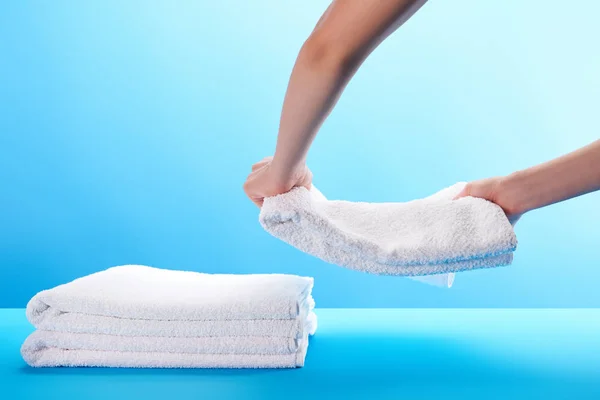 Partial view of person stacking clean soft white towels on blue — Stock Photo