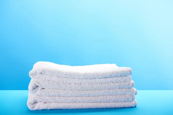 Pila de toallas blancas suaves limpias sobre fondo azul - foto de stock