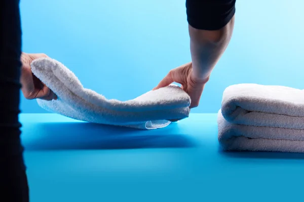 Cropped shot of person stacking clean white towels on blue — Stock Photo