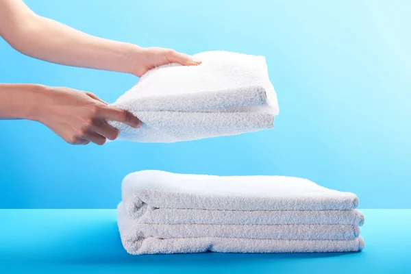 Cropped shot of person stacking clean white towels on blue — Stock Photo