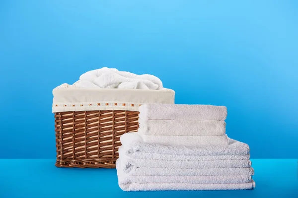 Close-up view of white clean towels and laundry basket on blue — Stock Photo