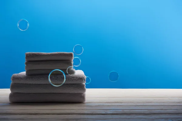 Serviettes blanches propres et bulles de savon sur fond bleu — Photo de stock