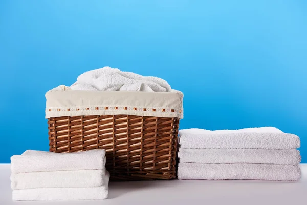 Vue rapprochée du panier à linge et des serviettes blanches douces propres sur bleu — Photo de stock