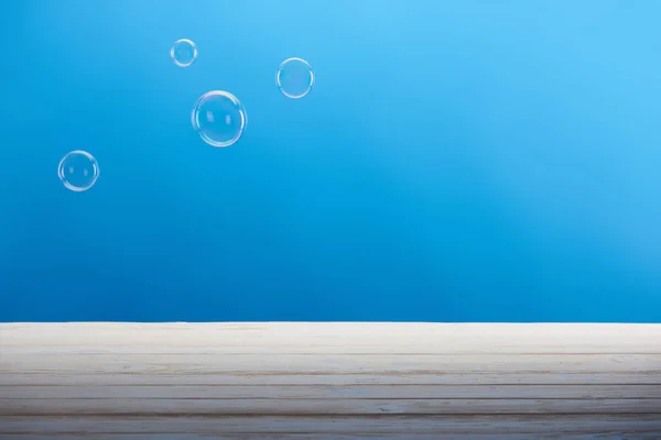 Limpar bolhas de sabão e superfície branca no fundo azul — Fotografia de Stock