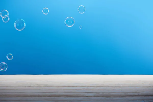 Bolhas de sabão e superfície branca no fundo azul — Fotografia de Stock