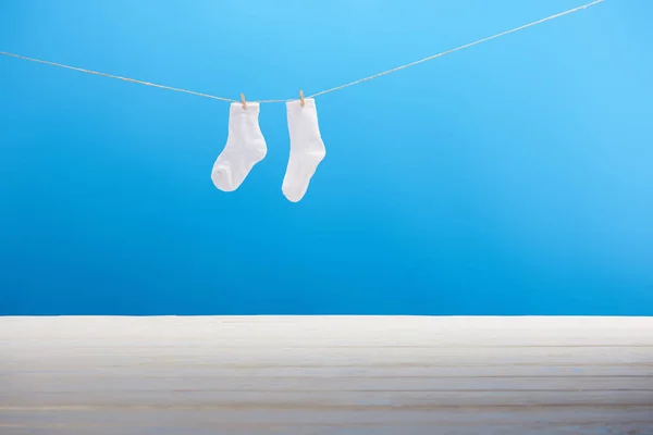 Saubere weiße Socken hängen an der Wäscheleine auf blauem Hintergrund — Stockfoto