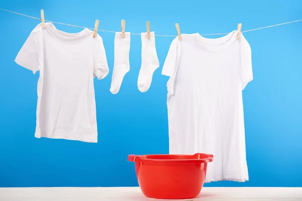 Lavabo rosso e vestiti bianchi puliti appesi sulla clothesline su blu — Foto stock