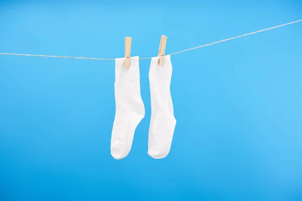 Saubere weiße Socken hängen an der Wäscheleine isoliert auf blauem Hintergrund — Stockfoto