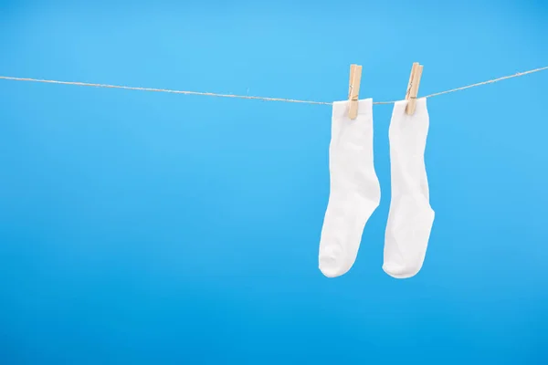 Close-up view of clean white socks hanging on rope isolated on blue — Stock Photo