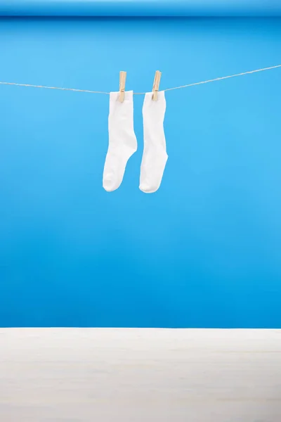 Chaussettes blanches propres suspendues sur corde à linge sur bleu — Photo de stock