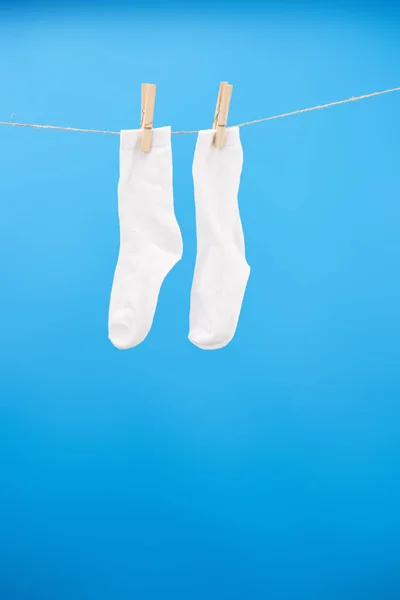 Close-up view of clean white socks hanging on clothesline isolated on blue — Stock Photo