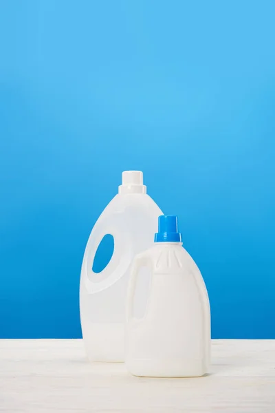 Récipients en plastique avec liquides de lessive sur bleu — Photo de stock