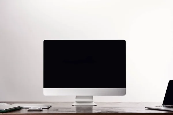 Monoblock computer with laptops on wooden table isolated on grey — Stock Photo