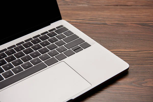 Partial view of laptop with blank screen on wooden table — Stock Photo