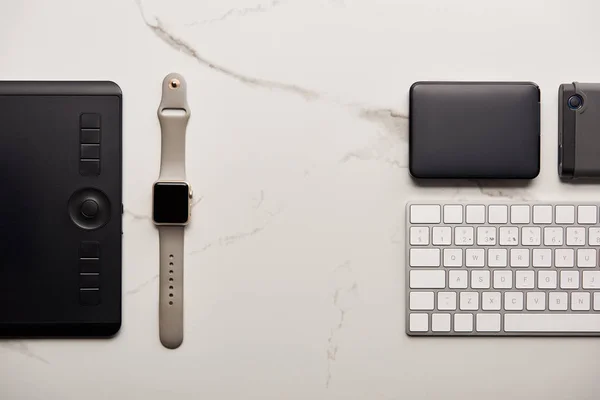 Flache Lage mit Grafik-Tablet mit tragbarer HDD, Smart Watch und drahtloser Tastatur auf weißer Marmoroberfläche — Stockfoto