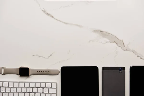 Vue de dessus de divers gadgets sans fil sur la surface de marbre blanc — Photo de stock