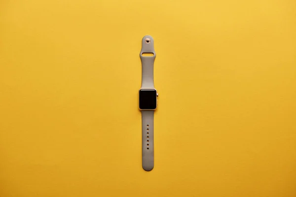 Vista superior del reloj inteligente con pantalla en blanco en la superficie amarilla — Stock Photo