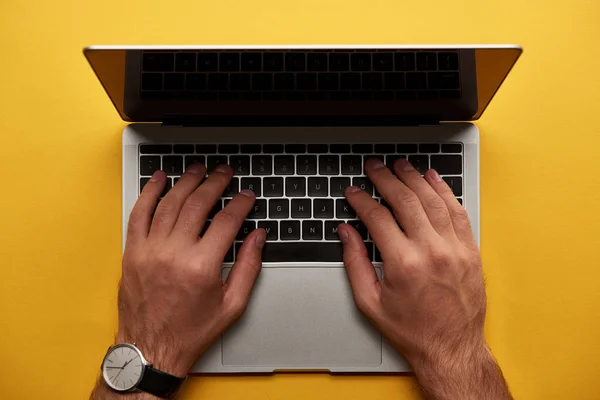 Обрезанный снимок человека с помощью ноутбука на желтой поверхности — стоковое фото