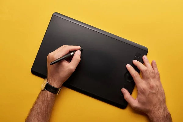 Обрезанный снимок художника с графическим планшетом на желтой поверхности — стоковое фото