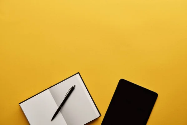 Top view of opened notebook and tablet on yellow surface — Stock Photo