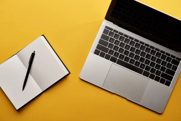 Top view of opened notebook and laptop on yellow surface — Stock Photo