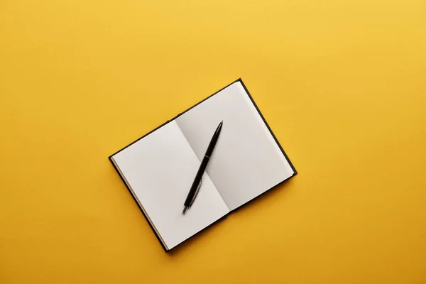 Top view of opened notebook and pen on yellow surface — Stock Photo