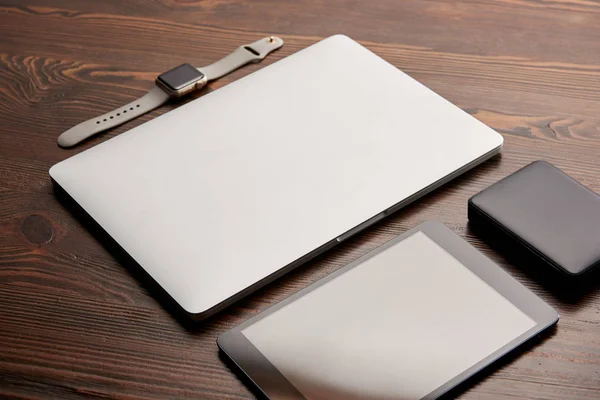 Крупный план ноутбука с цифровым планшетом, умные часы и портативный hdd на деревянном столе — стоковое фото