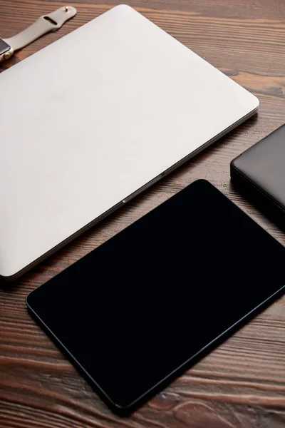 Close-up shot of laptop with tablet, smart watch and portable hdd on wooden table — Stock Photo